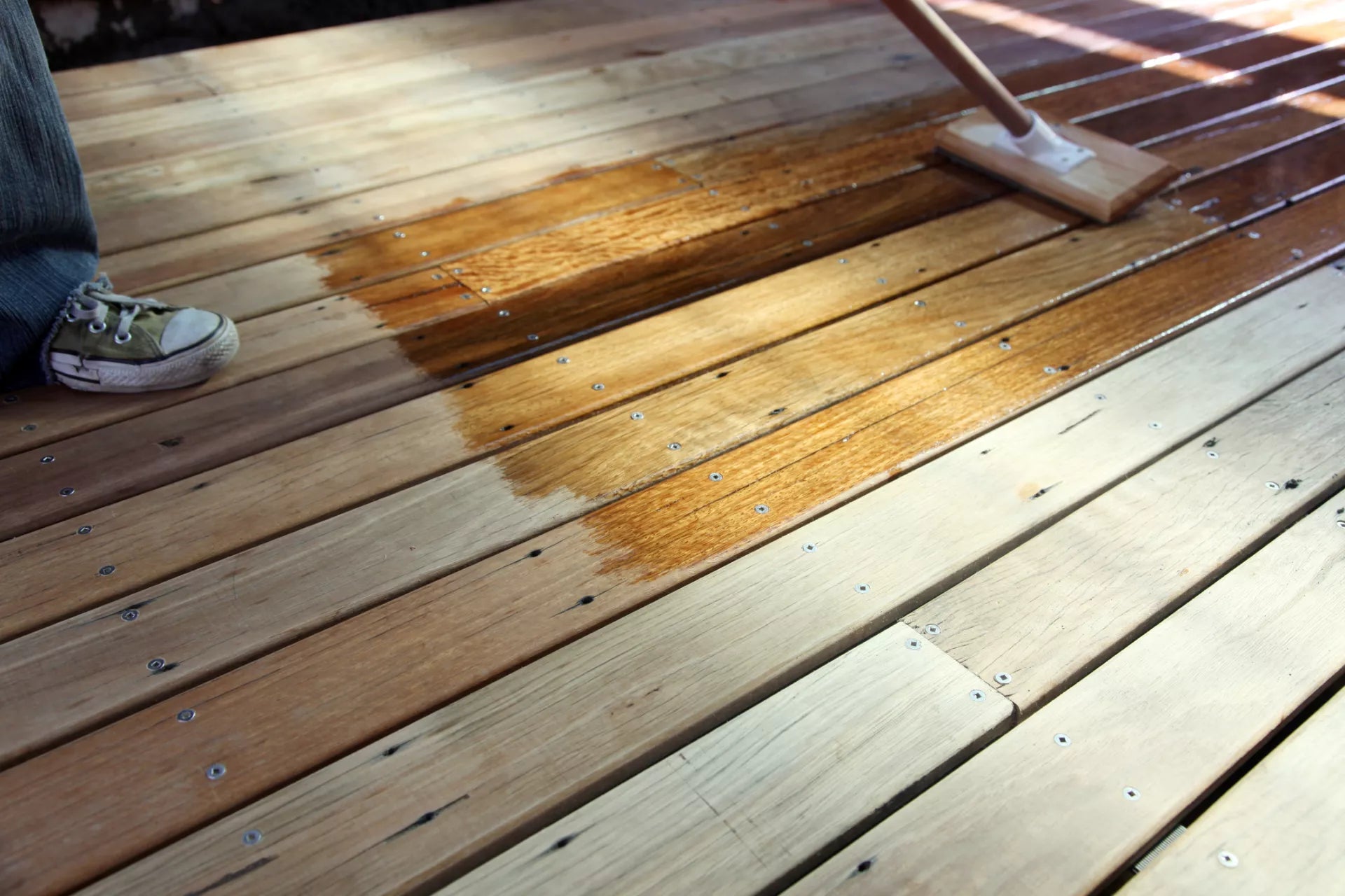 applying decking oil with a brush on t timber deck